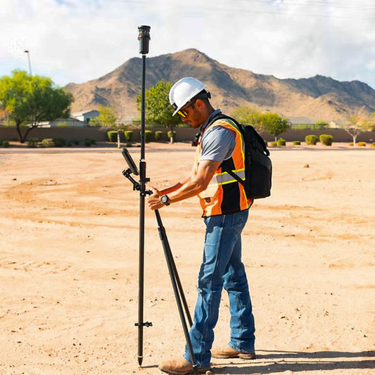Person in construction gear with pole and bipod on a desert landscape
