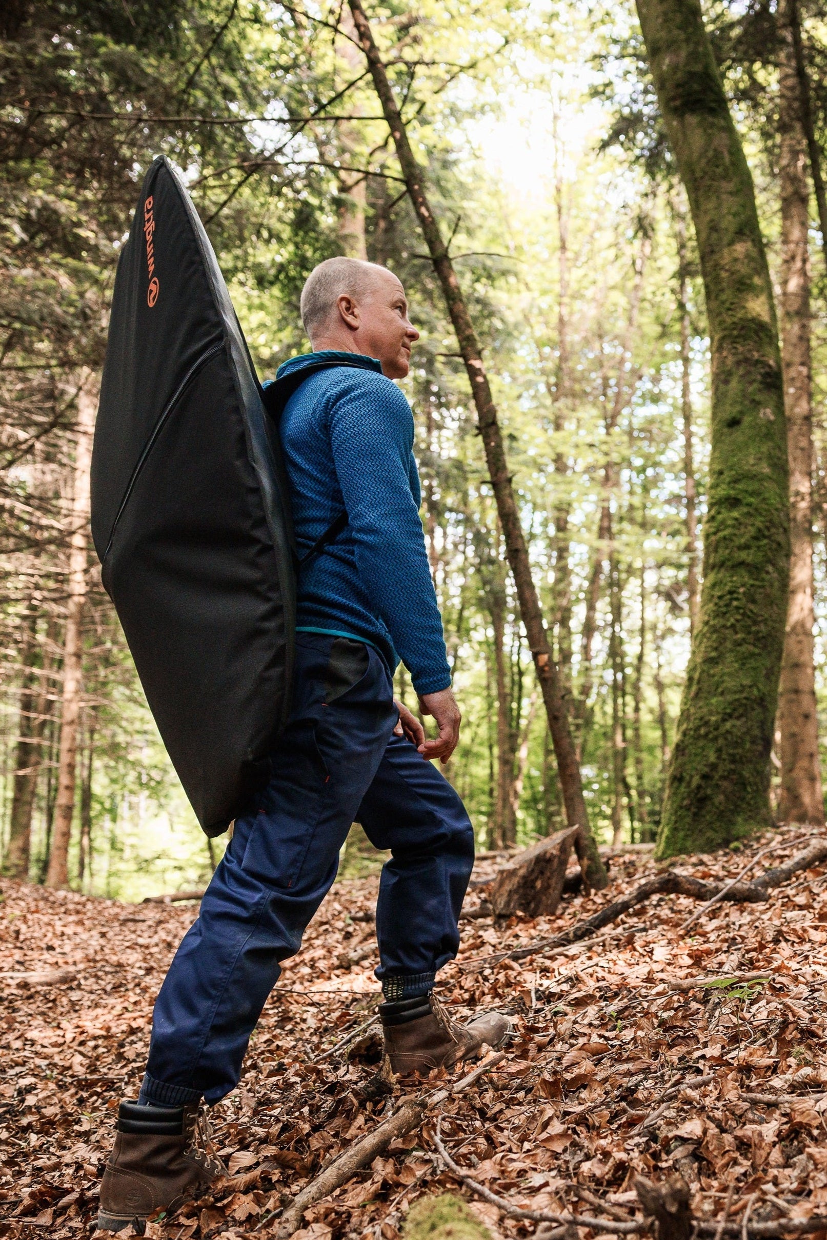 Person walking through a forest carrying a drone backpack