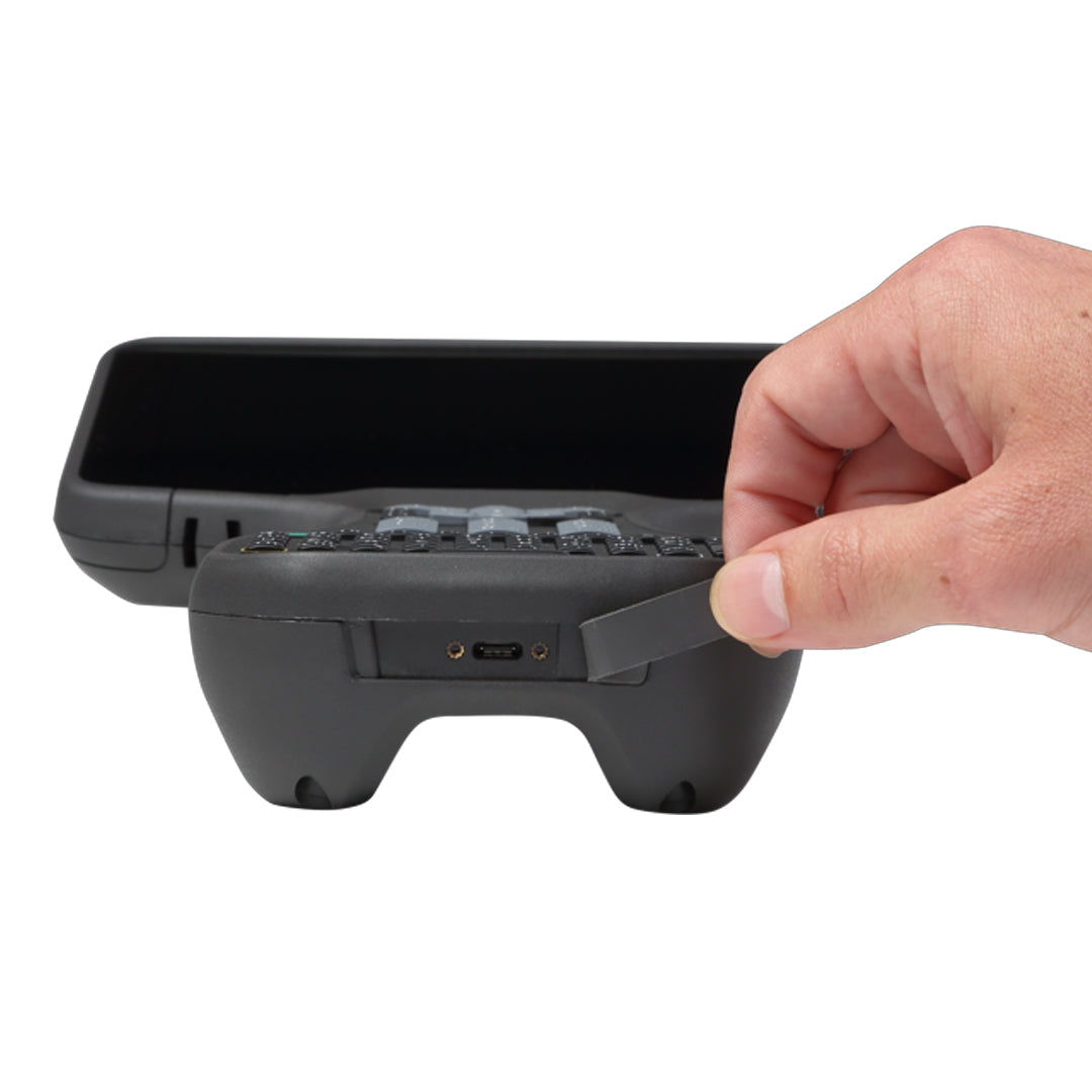 Hand holding Trimble TSC710 USB port dust cover open for observation