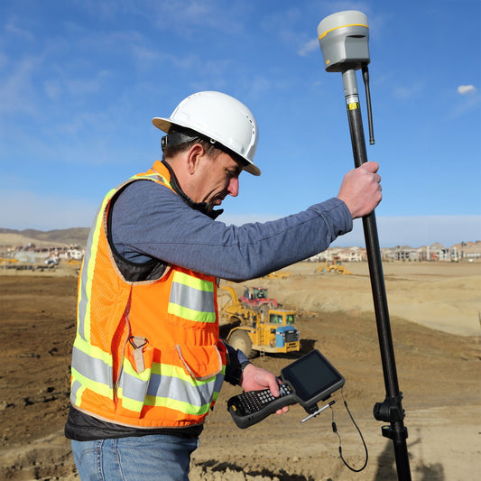 Person in construction gear using Trimble TSC710 and R980 on a construction site