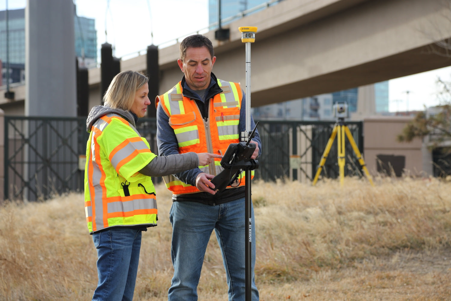Two surveyors in high-visibility vests using TSC710 Data Collector and SX12 Scanner.