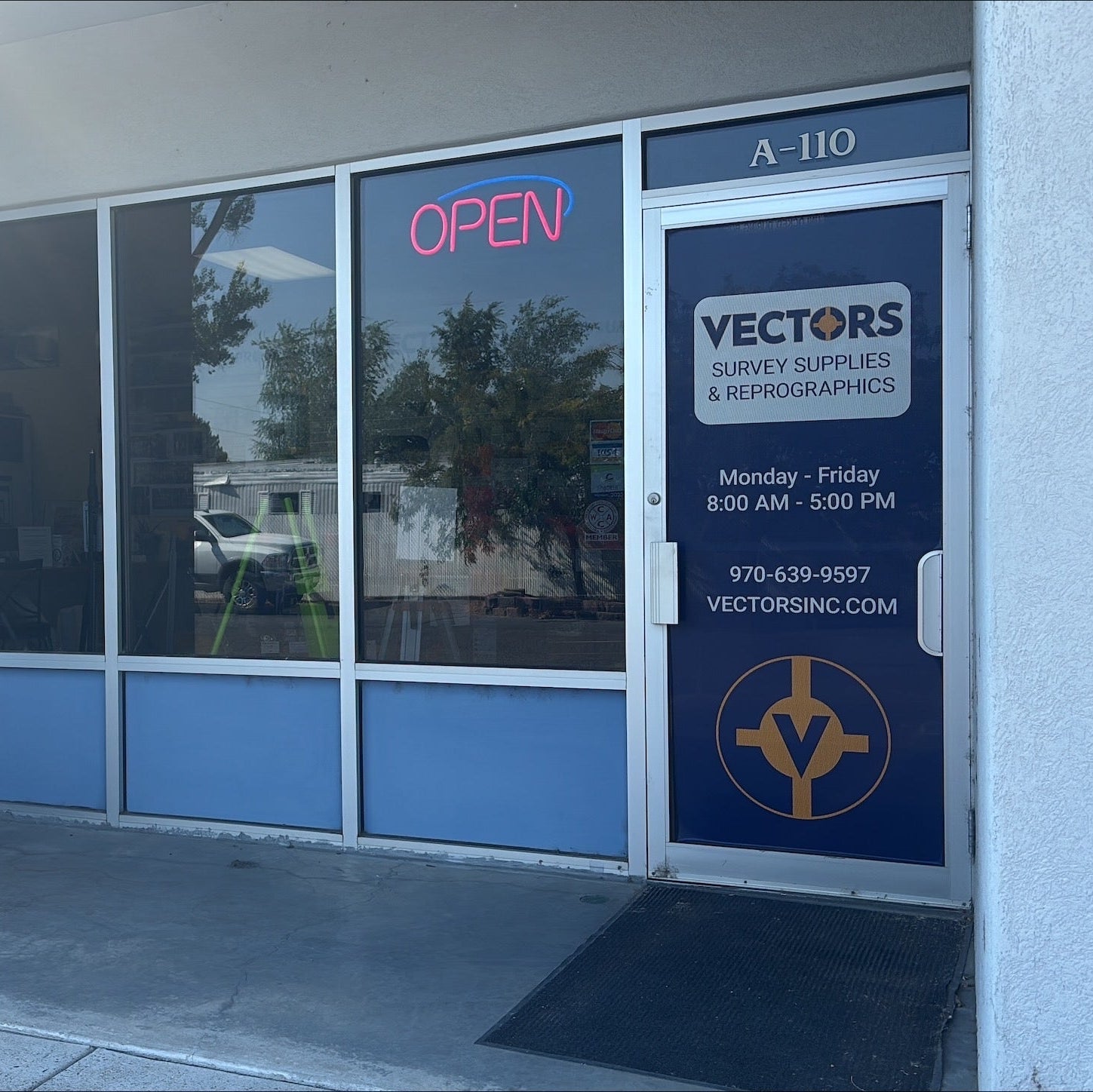 Storefront with 'Open' sign and 'Vectors' branding on a clear day.