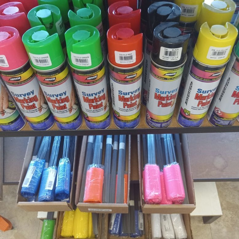 Shelf with colorful survey marking paint cans and markers.